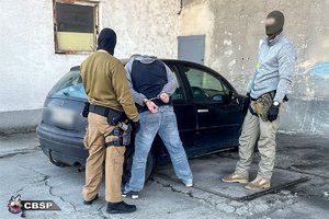 nieumundurowani policjanci z zatrzymanym mężczyzna przy samochodzie