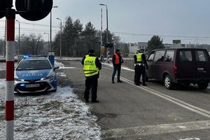 Widok na przejazd kolejowy. Po lewej radiowóz policyjny. Po prawej policjanci kontrolujący pojazd.
