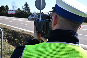 Umundurowany policjant wykonujący pomiar prędkości.