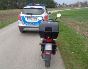 Motorower na pierwszym planie. W tle policyjny radiowóz.