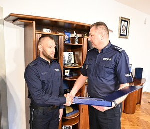 komendant wojewódzki policji w swoim gabinecie wręcza policjantom pamiątkowe grawertony