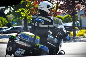 Policjant jadący na motocyklu policyjnym.