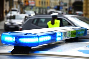 Sygnały świetlne radiowozu i umundurowana policjantka w tle podczas pracy na drodze.