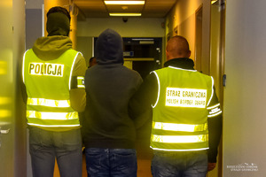 Policjant i strażnik graniczny prowadzący osobę zatrzymaną