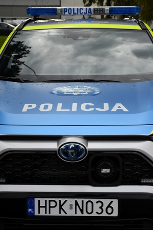 Policjanci i nowe radiowozy na placu.