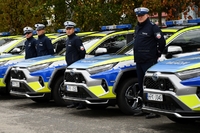Policjanci i nowe radiowozy na placu.