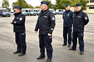 Policjanci i nowe radiowozy na placu.