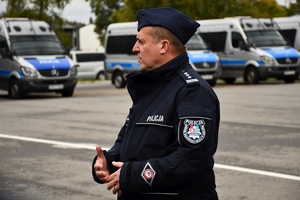 Policjanci i nowe radiowozy na placu.