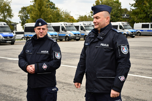 Policjanci i nowe radiowozy na placu.