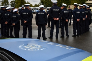 Policjanci i nowe radiowozy na placu.