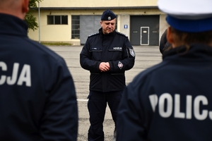 Policjanci i nowe radiowozy na placu.