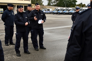 Policjanci i nowe radiowozy na placu.