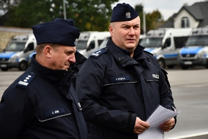 Policjanci i nowe radiowozy na placu.