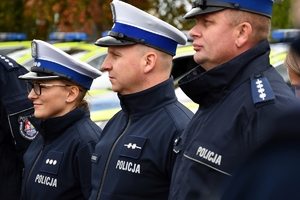 Policjanci i nowe radiowozy na placu.
