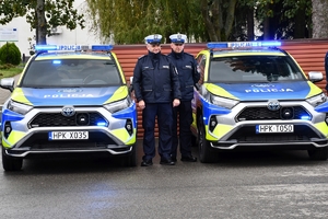 Policjanci i nowe radiowozy na placu.