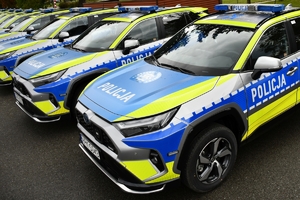 Policjanci i nowe radiowozy na placu.