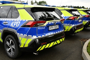 Policjanci i nowe radiowozy na placu.