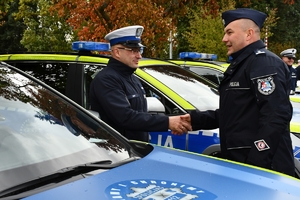 Policjanci i nowe radiowozy na placu.