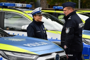 Policjanci i nowe radiowozy na placu.