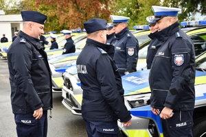 Policjanci i nowe radiowozy na placu.