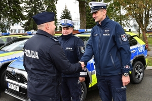 Policjanci i nowe radiowozy na placu.