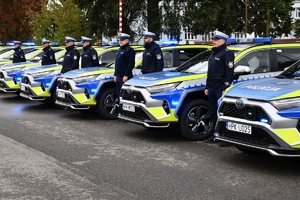 Policjanci i nowe radiowozy na placu.