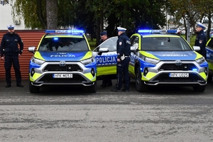 Policjanci i nowe radiowozy na placu.