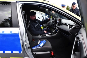 Policjanci i nowe radiowozy na placu.