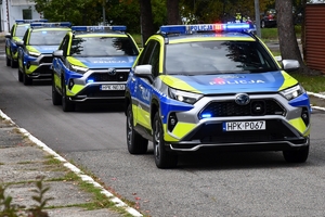 Policjanci i nowe radiowozy na placu.