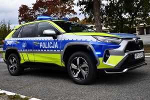 Policjanci i nowe radiowozy na placu.