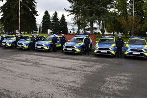 Policjanci i nowe radiowozy na placu.