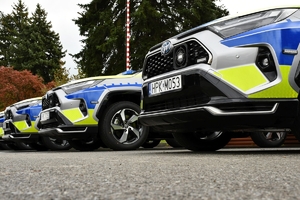 Policjanci i nowe radiowozy na placu.