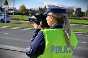 Policjanta trzymająca w ręku urządzenie służące do pomiaru prędkości pojazdów