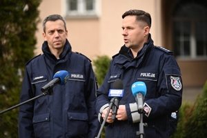 Dwaj policjanci i policjantka podczas udzielania wywiadów w trakcie briefingu przed budynkiem Komendy Wojewódzkiej Policji w Rzeszowie