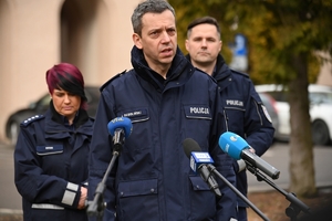 Dwaj policjanci i policjantka podczas udzielania wywiadów w trakcie briefingu przed budynkiem Komendy Wojewódzkiej Policji w Rzeszowie