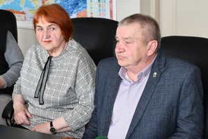 Uczestnicy spotkania w sali sztabowej Komendy Wojewódzkiej Policji w Rzeszowie. Uczestnicy siedzą przy stole, w tle na ścianie logo Komendy Wojewódzkiej Policji w Rzeszowie i napis  Komenda Wojewódzka Policji w Rzeszowie.