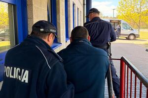 Policjanci prowadzą zatrzymanego mężczynę