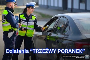 Dwoje policjantów stojących przy zatrzymanym do kontroli drogowej samochodzie. jeden z funkcjonariuszy sprawdza trzeźwość kierowcy