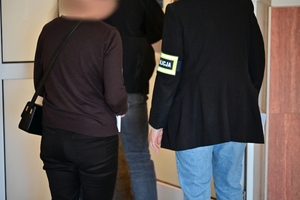Funkcjonariusze prowadzący kobietę podejrzaną o korupcję menadżerską