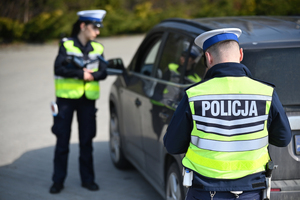 Policjanci podczas kontroli drogowej stojący przy samochodzie