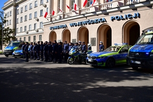 Policjanci oddają honory zmarłemu Koledze - upamiętnienie pod budynkiem Komendy Wojewódzkiej Policji w Rzeszowie, po prawej i lewej stronie stoją policyjne radiowozy z włączonymi sygnałami świetlnymi i dźwiękowymi.