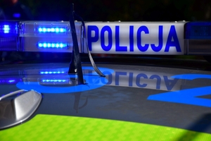 Policjanci oddają honory zmarłemu Koledze - upamiętnienie pod budynkiem Komendy Wojewódzkiej Policji w Rzeszowie, po prawej i lewej stronie stoją policyjne radiowozy z włączonymi sygnałami świetlnymi i dźwiękowymi.