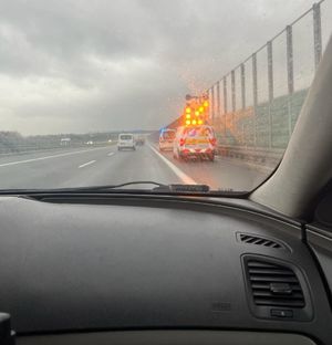 a zdjeciu autostrada. Z prawej strony pojazd Generalnej Dyrekcji Dróg  Krajowych i Autostrad, z włączonymi na dachu światłami barwy pomarańczowej. Przed nim karetka z włączonymi światłami na dachu barwy niebieskiej. W tle inne pojazdy.