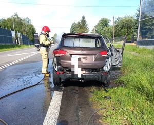 Na miejscu ugaszony samochód, z lewej strony stoi strażak.