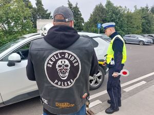 Na zdjęciu umundurowany policjant ruchu drogowego podczas kontroli drogowej i członkowie klubu motocyklowego.