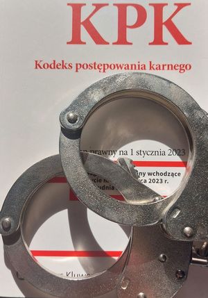 Na zdjęciu kodeks postępowania karnego, na którym leżą policyjne kajdanki.