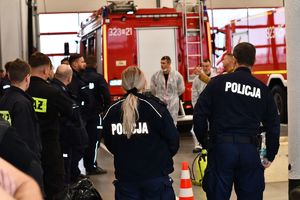 Na zdjęciu umundurowaniu policjanci oraz strażacy w tle wozy strażackie.