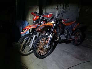 Na zdjeciu dwa motocykle typu cross, koloru pomarańczowego.