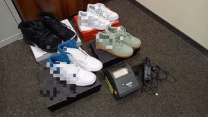 Na zdjęciu cztery pary butów sportowych, które stoją na kartonowych opakowaniach. Obok leży drukarka.