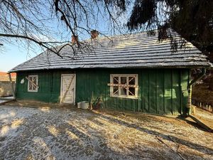 Na zdjęciu drewniany dom w kolorze zielonym , okna i drzwi wejściowe są zagrodzone taśmą.